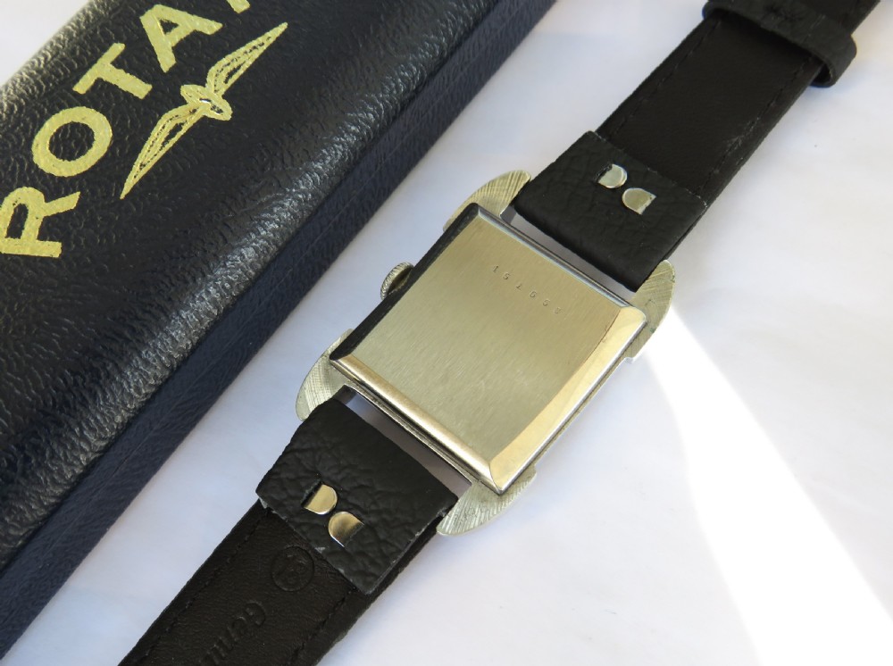 A 1950s gents Rotary wristwatch featuring a rectangular silver-tone case, cream dial with Arabic numerals, sub-seconds dial, and a black leather strap. View IV