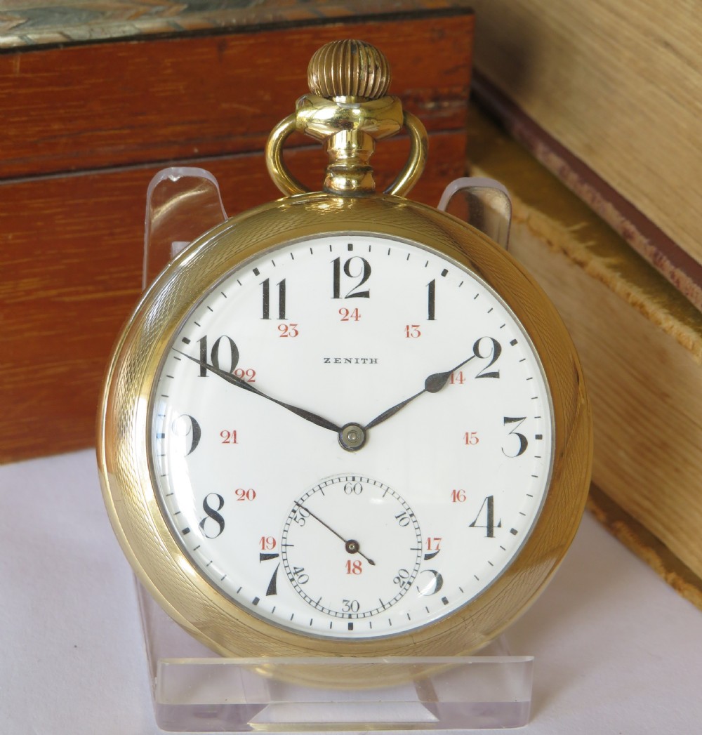 An open-face antique gold-tone pocket watch featuring a white enamel dial, black Arabic hour numerals, red 24-hour markings, and a subsidiary seconds sub-dial. View II