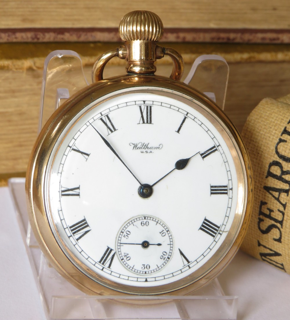 An open-face gold-filled pocket watch featuring a white enamel dial with black Roman numerals and a sub-seconds dial. View II