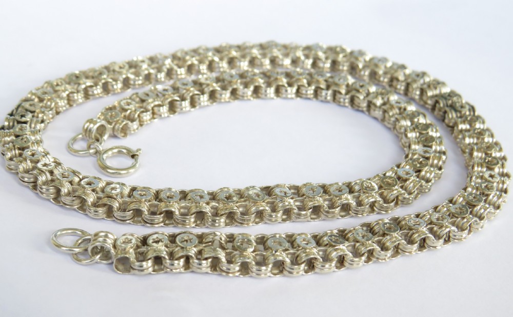 An antique silver chain featuring repeating interlocking links stamped with circular star motifs and secured with a bolt ring clasp.