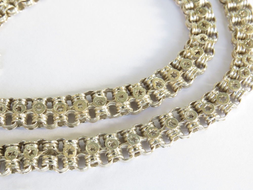 An antique silver chain featuring repeating interlocking links stamped with circular star motifs and secured with a bolt ring clasp. View II