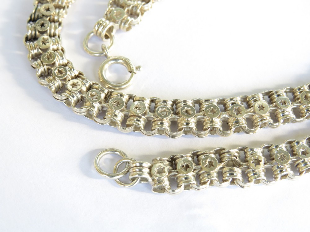 An antique silver chain featuring repeating interlocking links stamped with circular star motifs and secured with a bolt ring clasp. View III