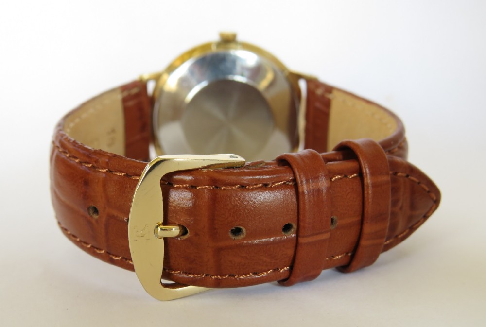 A 1960s Smiths Astral gents wristwatch featuring a gold-toned circular case, off-white dial with gold numerals, and a brown leather strap. View III