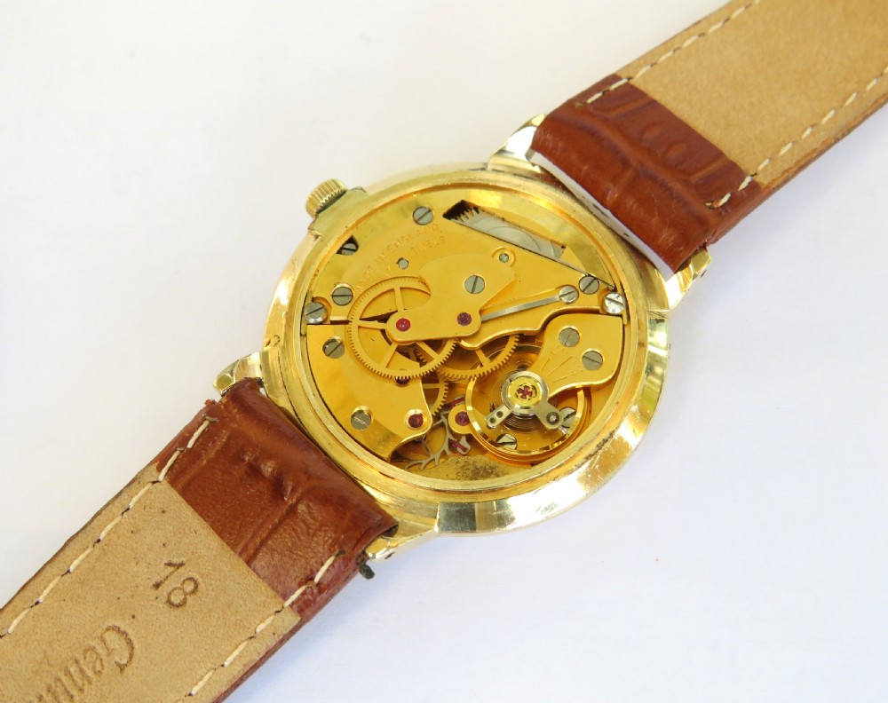 A 1960s Smiths Astral gents wristwatch featuring a gold-toned circular case, off-white dial with gold numerals, and a brown leather strap. View V