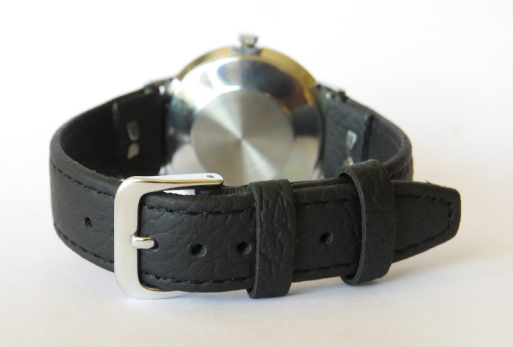 A 1960s gents Smiths Astral wristwatch featuring a round cream dial with black Arabic numerals, silver-toned metal case, and a black leather strap. View IV