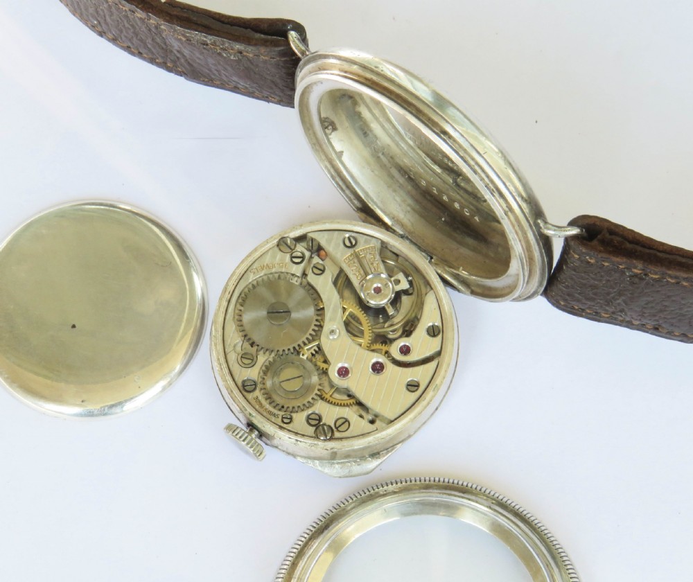 A 1930s gentlemans silver hermetic wrist watch with a circular coin-edge bezel, white enamel dial, sub-seconds display, and brown leather strap. View III