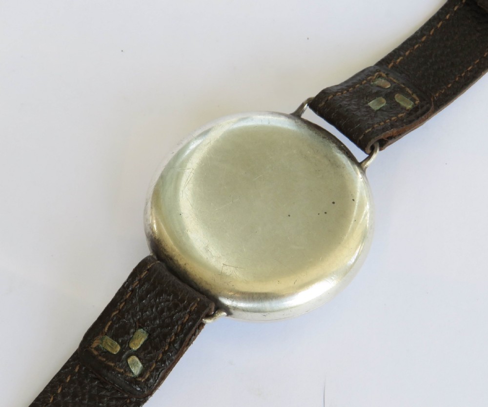 A 1930s gentlemans silver hermetic wrist watch with a circular coin-edge bezel, white enamel dial, sub-seconds display, and brown leather strap. View VI