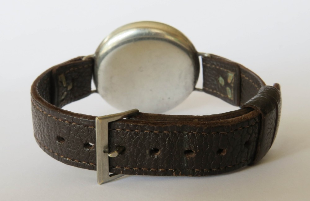 A 1930s gentlemans silver hermetic wrist watch with a circular coin-edge bezel, white enamel dial, sub-seconds display, and brown leather strap. View VII