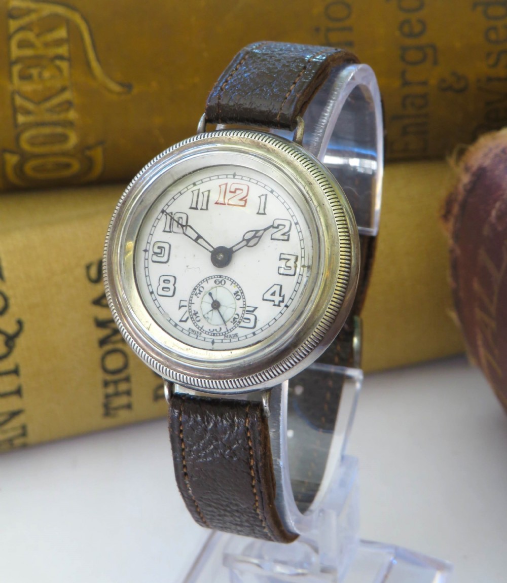 A 1930s gentlemans silver hermetic wrist watch with a circular coin-edge bezel, white enamel dial, sub-seconds display, and brown leather strap.