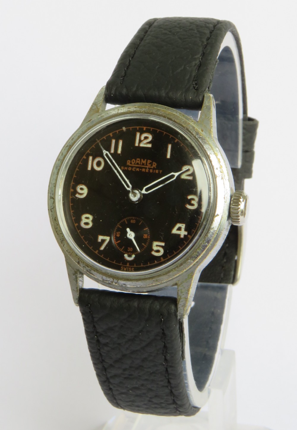A 1940s Roamer gents wristwatch featuring a round black dial with Arabic numerals, a sub-second dial at six oclock, a chrome-plated case, and a textured black leather strap.