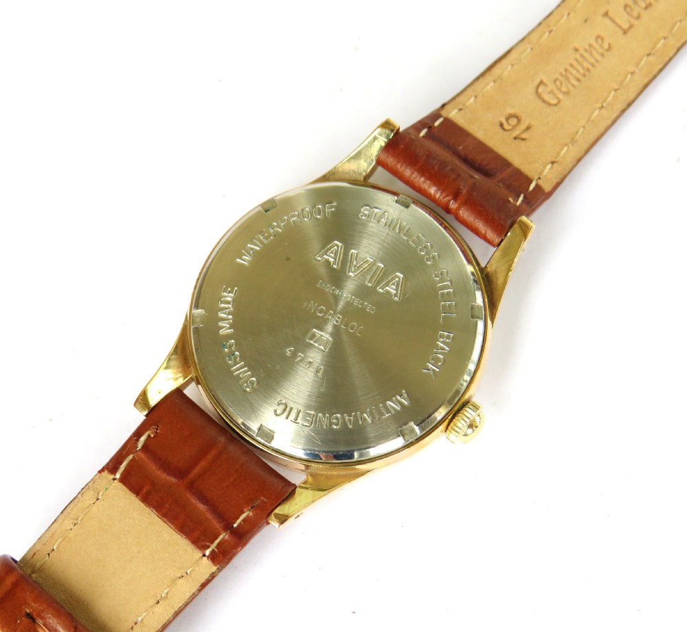A gents 1960s Avia Olympic wrist watch featuring a gold-toned circular case, cream dial with Arabic numerals, and a brown leather strap. View III