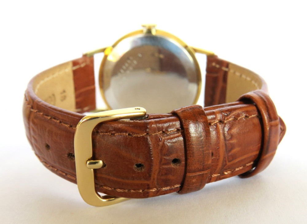 A 1960s Certina gents wristwatch featuring a gold dial, baton hour markers, and a brown leather strap alongside its red presentation box. View IV