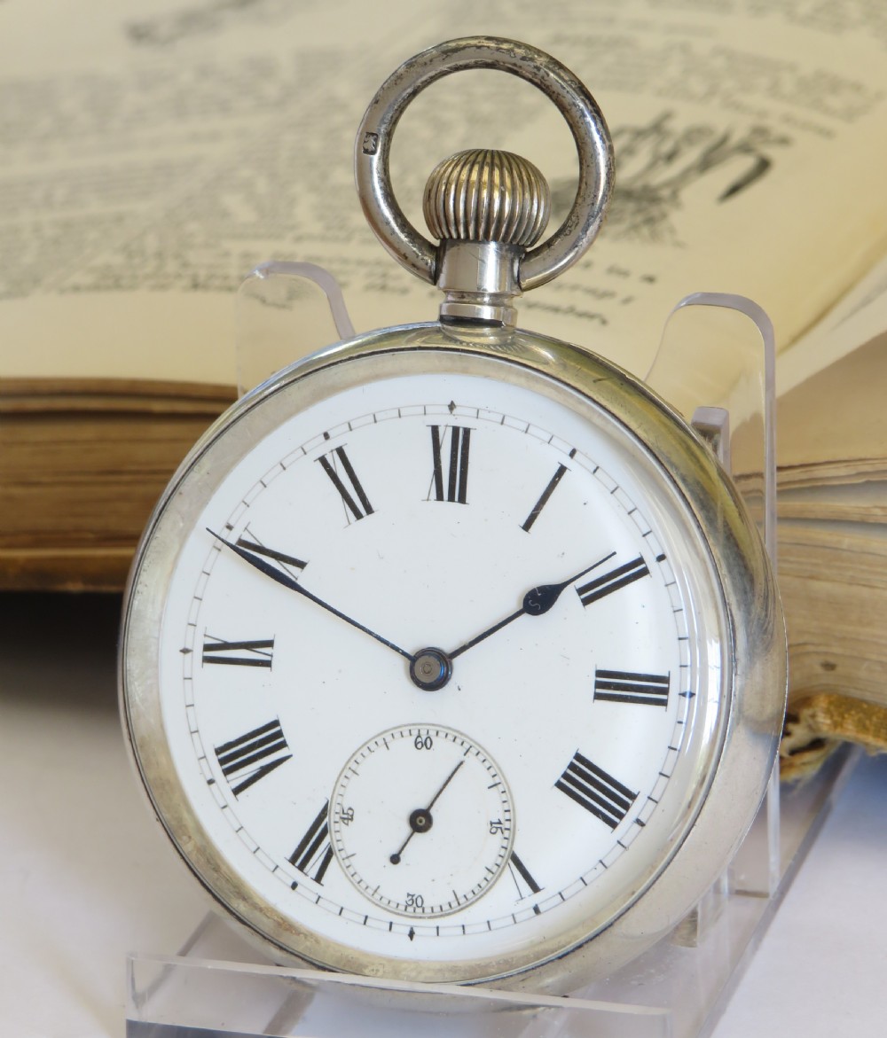An antique open-face silver pocket watch featuring a white enamel dial with black Roman numerals and a subsidiary seconds dial at the base.