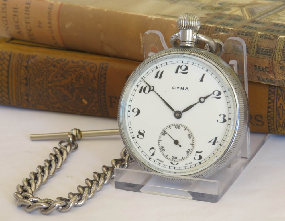 A 1930s Cyma open-face pocket watch featuring a white dial, black Arabic numerals, a sub-seconds dial, and a silver-toned curb chain with a T-bar.