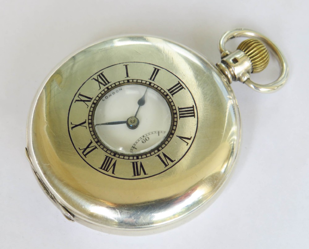 An antique silver half-hunter pocket watch featuring an outer enamel chapter ring with Roman numerals around a central circular glass window.