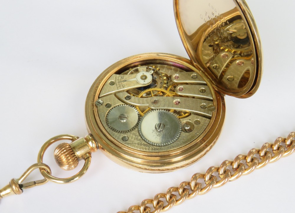 A gold-toned 1930s Cyma stem-winding pocket watch with a white enamel dial, black Arabic numerals, and a curb-link Albert chain with a T-bar. View IV