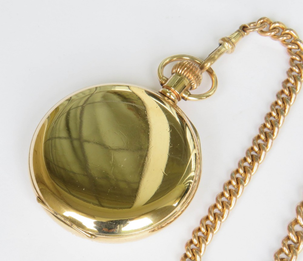 A gold-toned 1930s Cyma stem-winding pocket watch with a white enamel dial, black Arabic numerals, and a curb-link Albert chain with a T-bar. View V