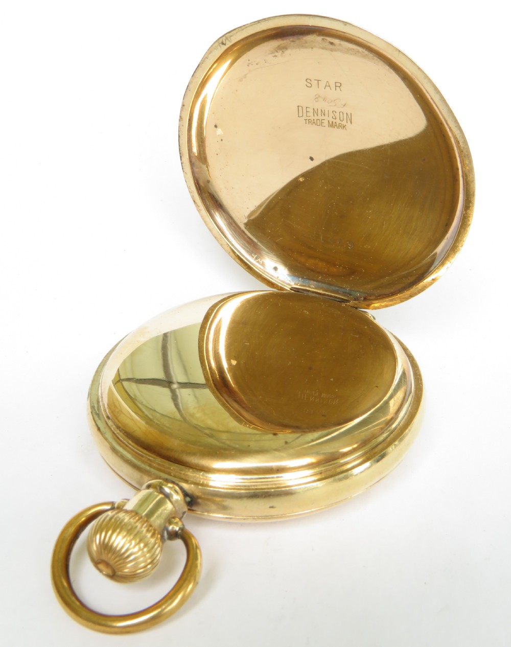 A gold-toned antique Waltham half hunter pocket watch featuring a central glass window surrounded by black Roman numerals on the outer casing. View V