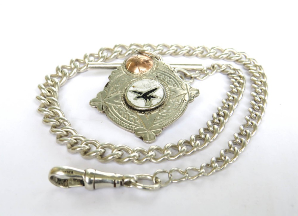 A silver curb link pocket watch chain featuring a T-bar, swivel clasp, and a shield-shaped sports fob with enamel detailing.