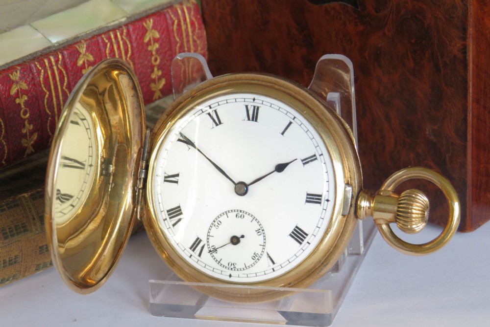 An open antique gold full hunter pocket watch with a white enamel dial, black Roman numerals, and a subsidiary seconds sub-dial.