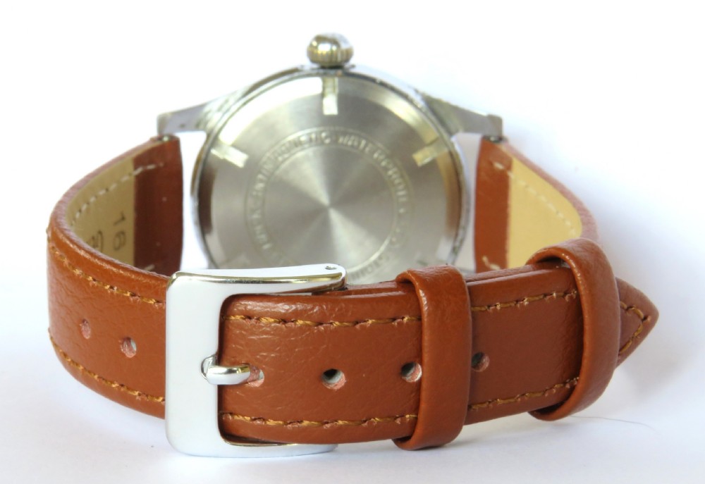 A 1950s gents mechanical wristwatch featuring a round metal case, cream two-tone dial with Arabic numerals, sub-seconds dial, and a tan leather strap. View V