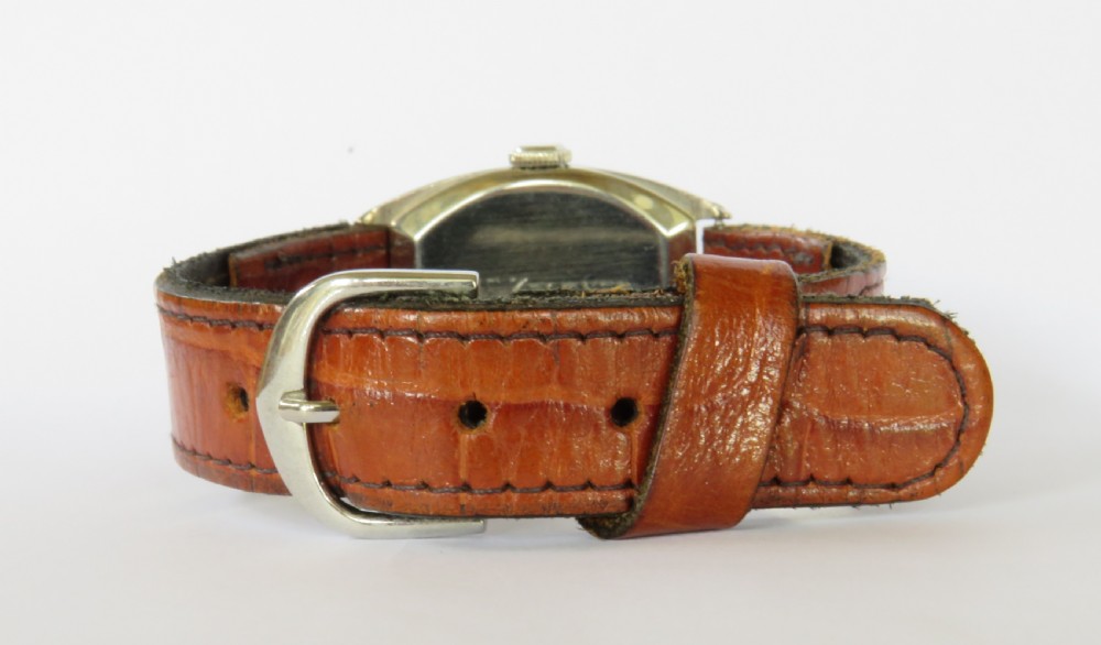 A 1930s Art Deco gents Hamilton wristwatch with a gold-toned tonneau case, cream dial, Arabic numerals, sub-seconds dial, and brown leather strap. View IV