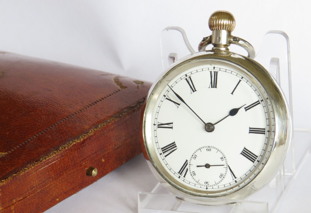 An antique silver open-face pocket watch featuring a white enamel dial with black Roman numerals and a sub-seconds dial.