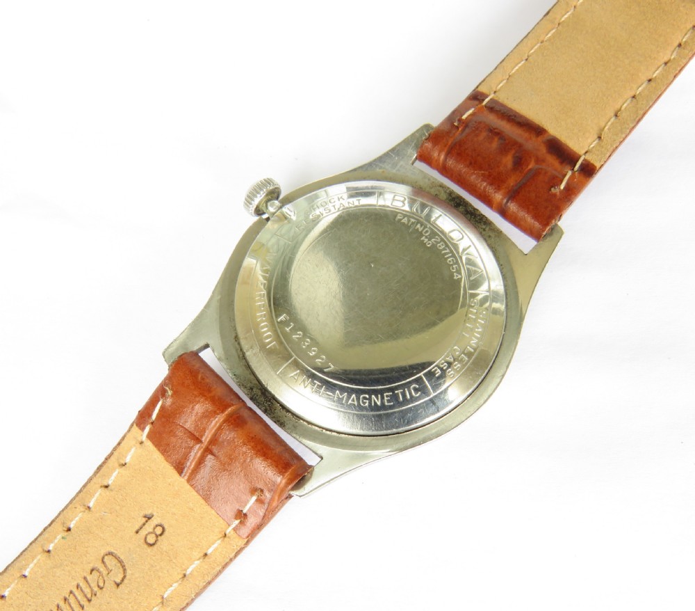A 1961 gents Bulova wrist watch with a silver-tone case, cream dial with gold Arabic numerals, sub-seconds dial, and a brown leather strap. View V