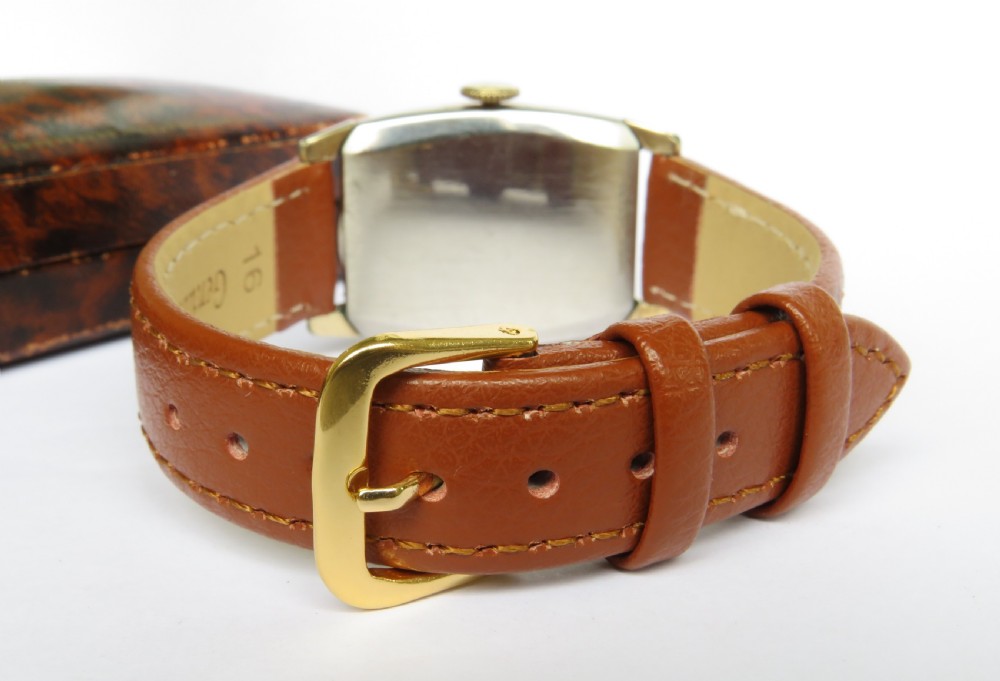 A 1948 Elgin mens wristwatch featuring a rectangular gold-toned case, cream dial with gold Arabic numerals, sub-seconds dial, and tan leather strap. View VI