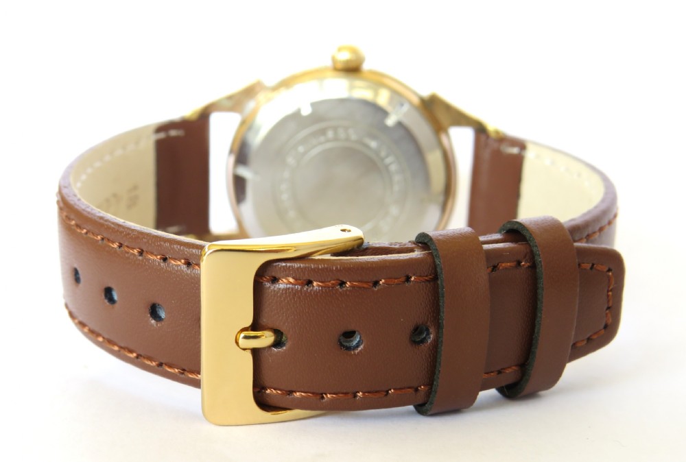 A gents vintage 1950s wristwatch featuring a gold-plated case, textured cream dial with Arabic numerals, and a brown leather strap. View V