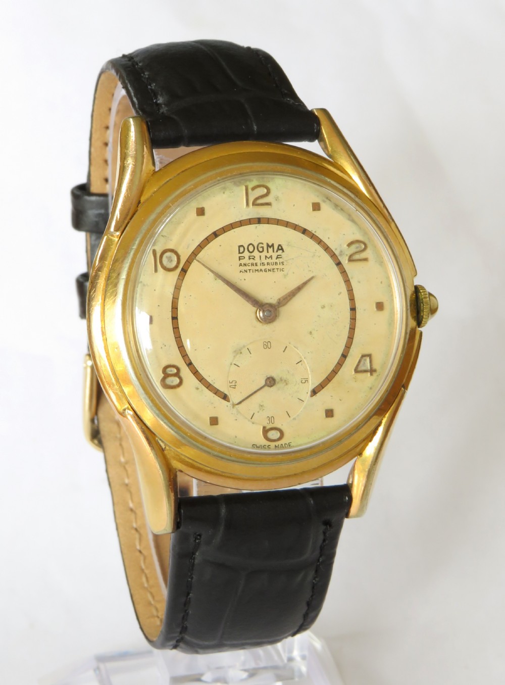 A 1950s gents Dogma Prima wristwatch featuring a gold-toned case, champagne dial with sub-seconds subdial, and black leather strap. View II