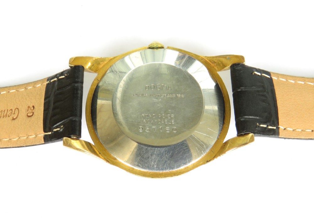 A 1950s gents Dogma Prima wristwatch featuring a gold-toned case, champagne dial with sub-seconds subdial, and black leather strap. View IV