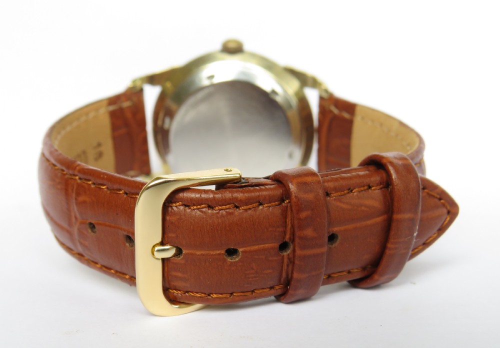 A mens 1950s Wittnauer automatic wristwatch featuring a circular gold-plated case, cream dial with dart hour markers, and a brown leather crocodile-embossed strap. View IV