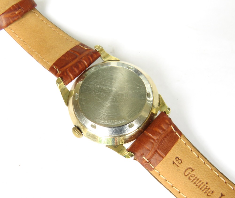 A mens 1950s Wittnauer automatic wristwatch featuring a circular gold-plated case, cream dial with dart hour markers, and a brown leather crocodile-embossed strap. View V