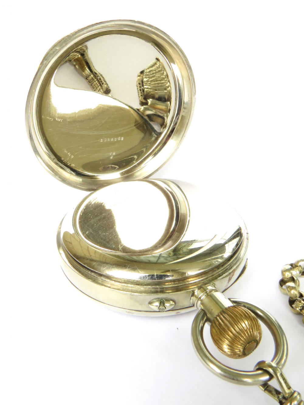 An antique nickel-cased goliath open-face pocket watch featuring a white enamel dial with Roman numerals, an eight-day movement marking, and an attached decorative brass chain. View III