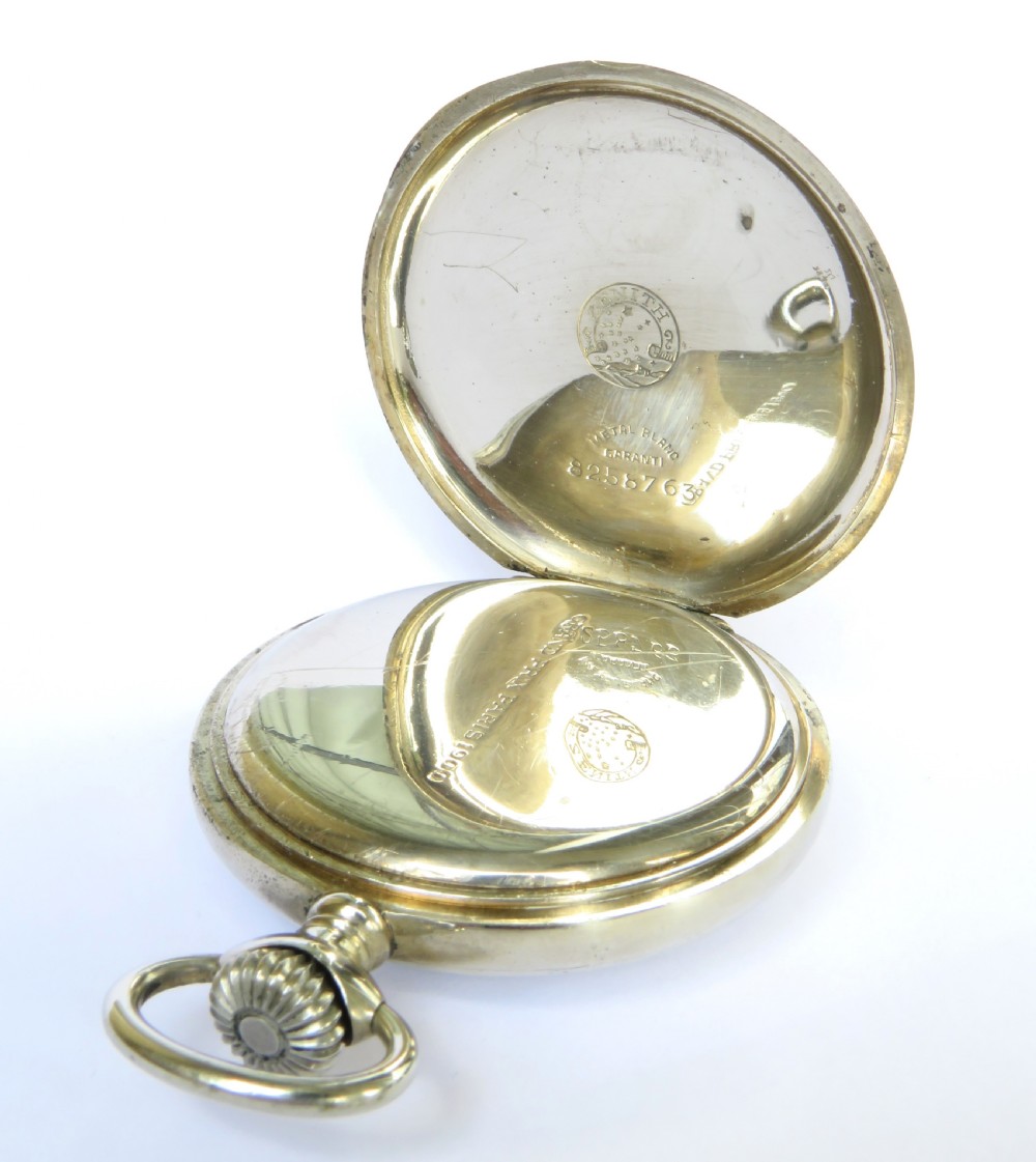 A 1939 Zenith open-face pocket watch featuring a white enamel dial with black Arabic numerals, secondary red 24-hour markers, a subsidiary seconds dial, and a metallic silver case. View III