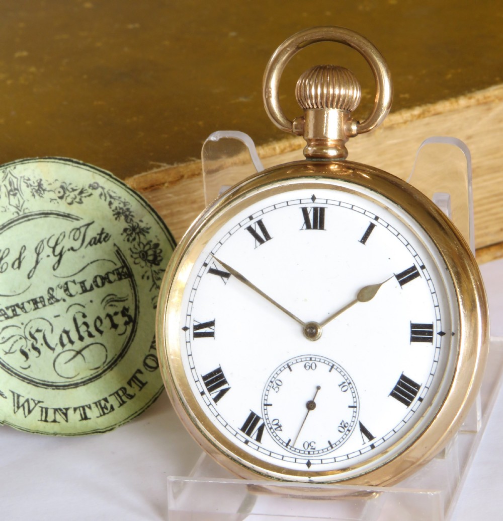 A 1930s open-face pocket watch featuring a gold-toned casing, white enamel dial with black Roman numerals, and a subsidiary seconds sub-dial at six oclock.