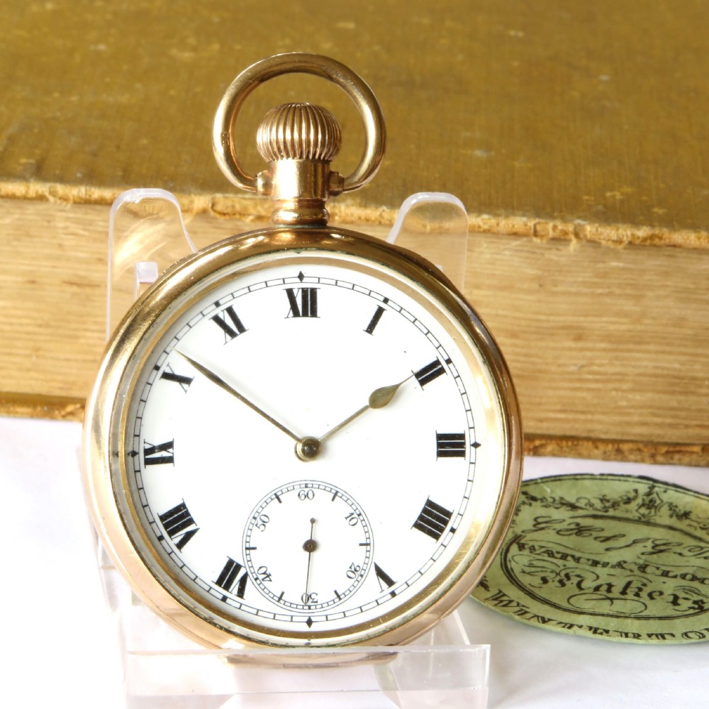 A 1930s open-face pocket watch featuring a gold-toned casing, white enamel dial with black Roman numerals, and a subsidiary seconds sub-dial at six oclock. View II