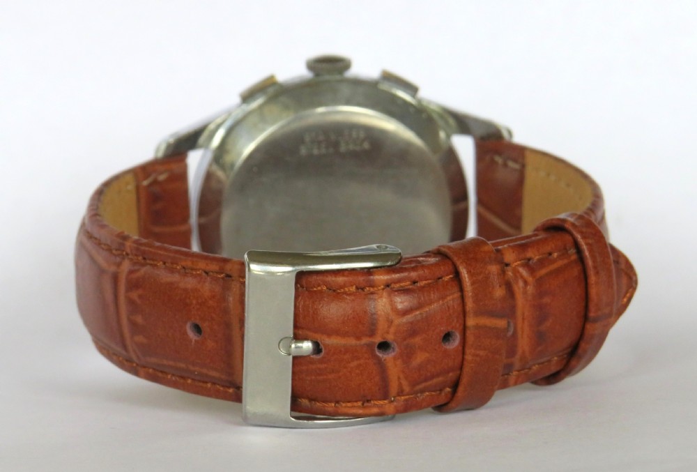 A vintage Enicar chronograph wrist watch featuring a cream dial with telematics scales, two sub-dials, stainless steel case, and a brown leather strap. View V