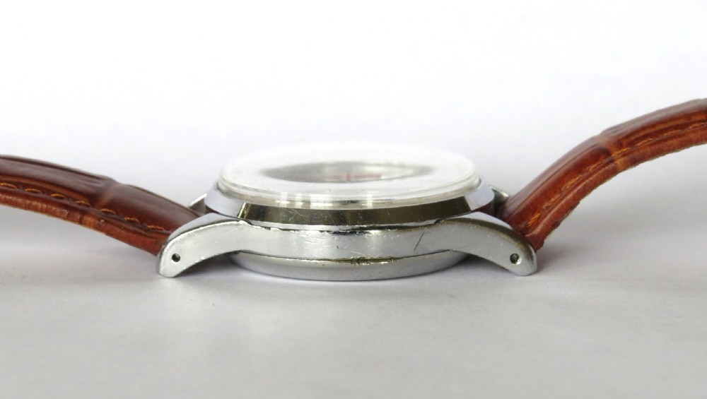 A vintage Enicar chronograph wrist watch featuring a cream dial with telematics scales, two sub-dials, stainless steel case, and a brown leather strap. View VI