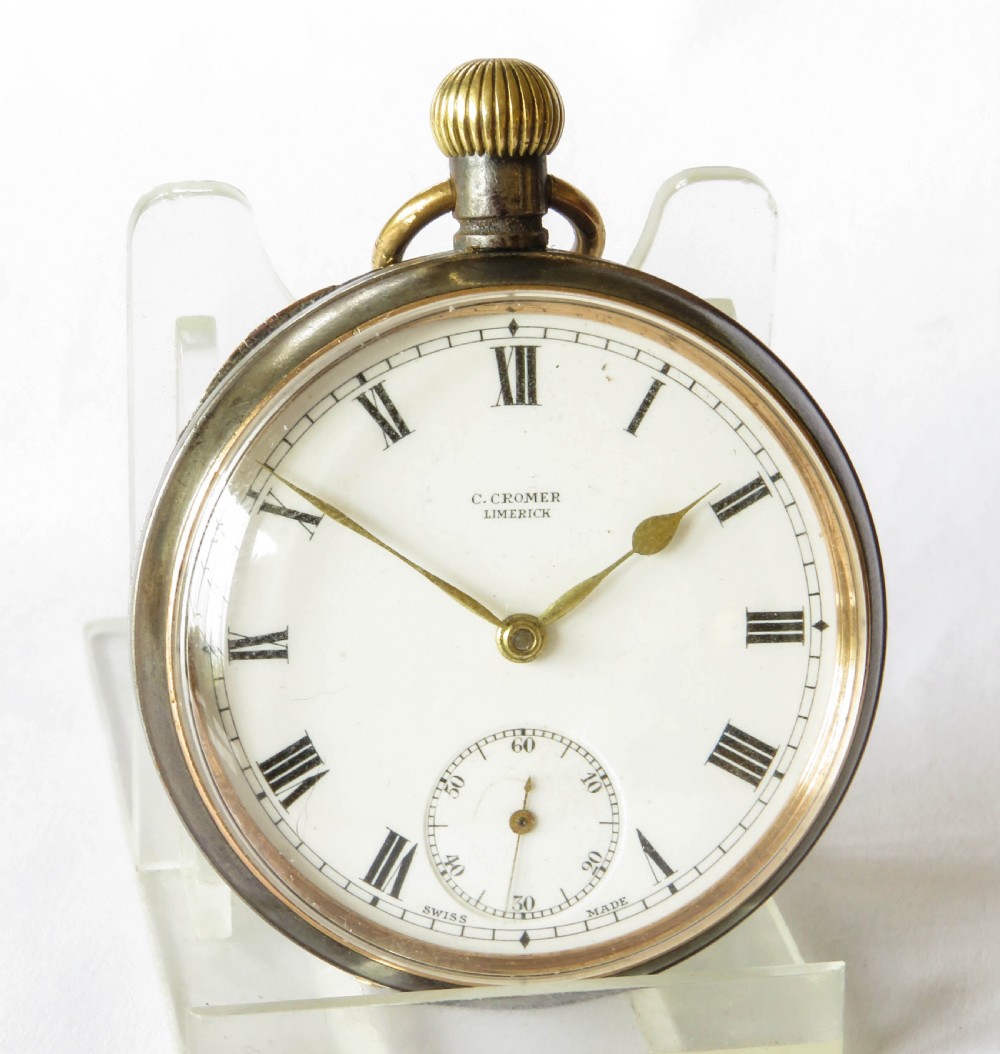 An antique open-face gunmetal pocket watch with a white enamel Roman numeral dial and brass Albert chain, set inside a red presentation case. View III