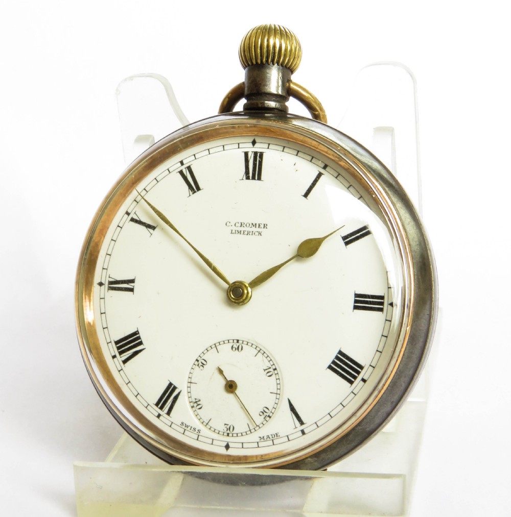 An antique open-face gunmetal pocket watch with a white enamel Roman numeral dial and brass Albert chain, set inside a red presentation case. View IV