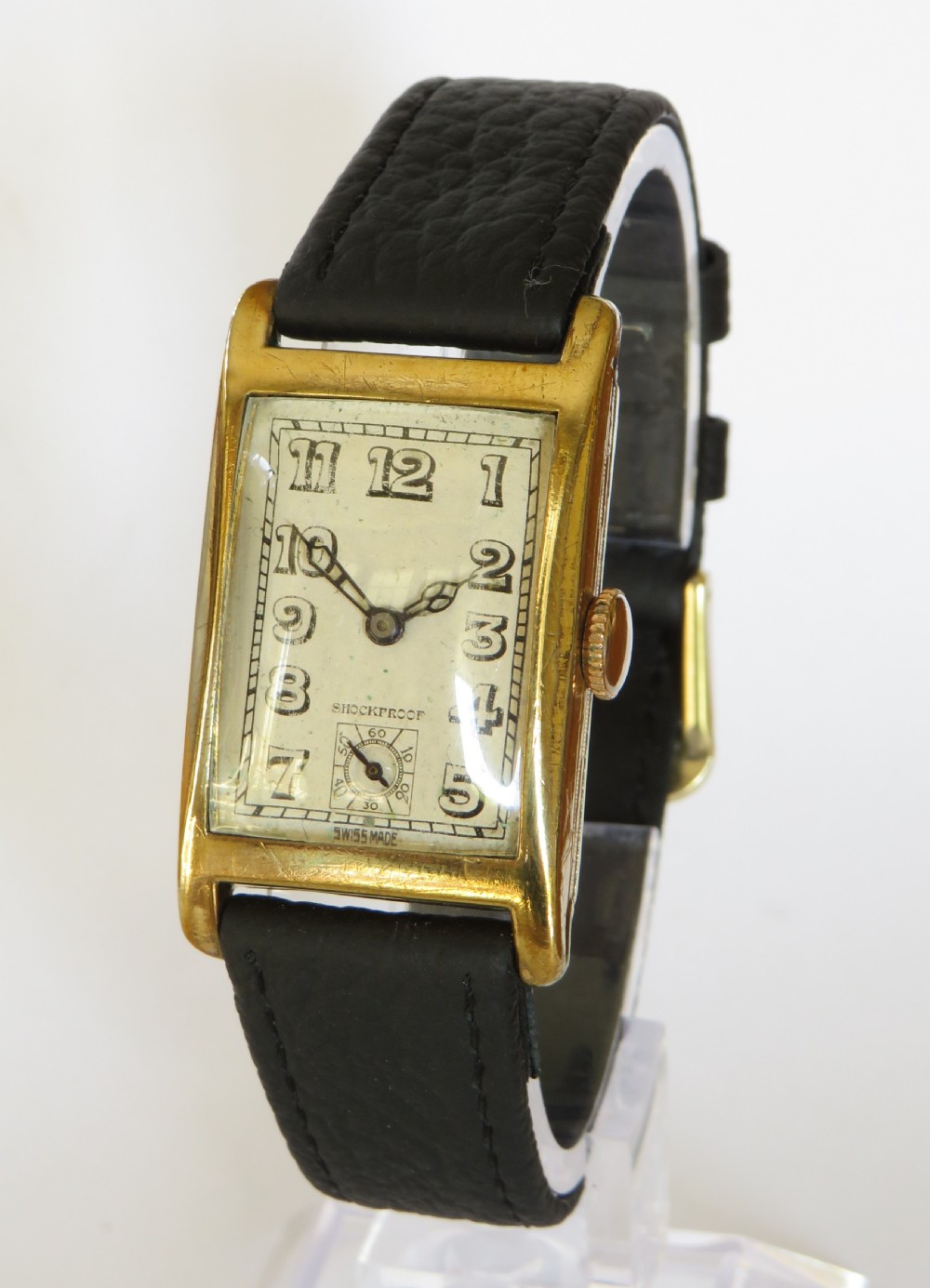 A 1930s rectangular Art Deco wristwatch by Rotary with a gold-plated case, cream dial with Arabic numerals, sub-seconds subdial, and a black leather strap.