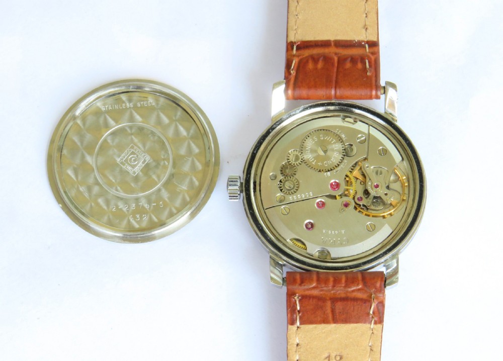 A 1950s Cyma Watersport gentlemans wristwatch featuring a light champagne dial with Arabic numerals, a metallic case, and a textured brown leather strap. View III