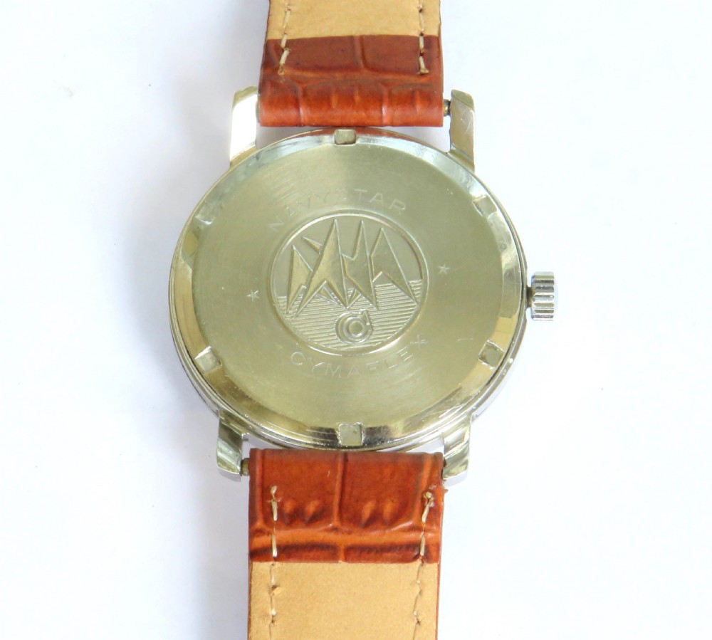 A 1950s Cyma Watersport gentlemans wristwatch featuring a light champagne dial with Arabic numerals, a metallic case, and a textured brown leather strap. View IV