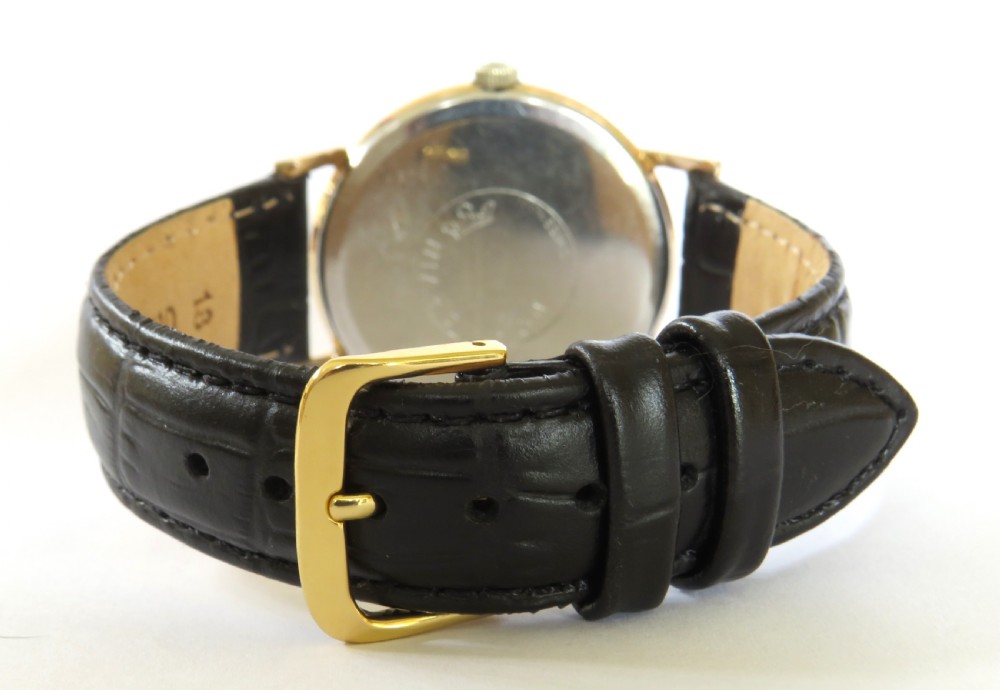 A 1960s vintage Marvin Hermetic gents wrist watch featuring a gold-toned circular case, champagne dial with applied baton hour markers, and a textured black leather strap. View V