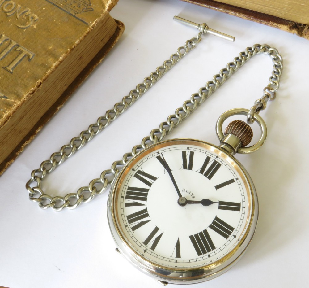 An open-face Goliath pocket watch featuring a white enamel dial with black Roman numerals and an attached silver-toned metal curb chain. View II