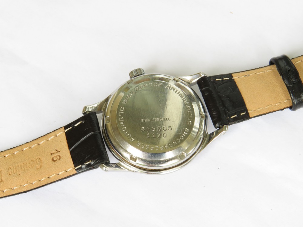 A 1950s gentlemens Primula Swiss automatic wristwatch featuring a silver-tone case, cream dial with gold-tone Arabic numerals, sub-seconds dial, and a black leather strap. View IV