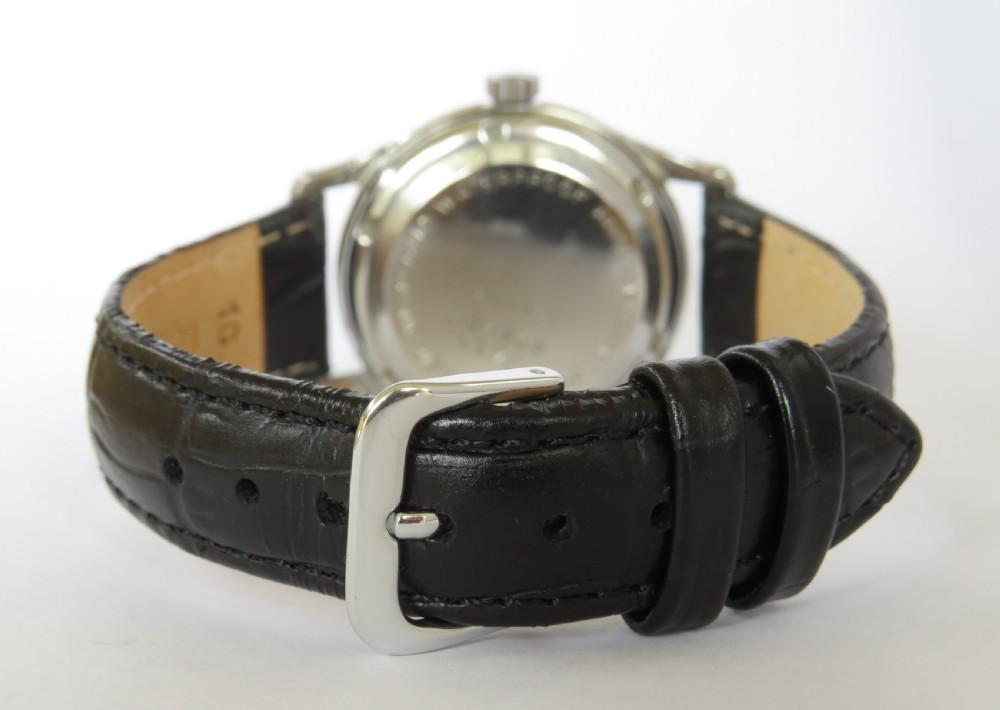 A 1950s gentlemens Primula Swiss automatic wristwatch featuring a silver-tone case, cream dial with gold-tone Arabic numerals, sub-seconds dial, and a black leather strap. View V