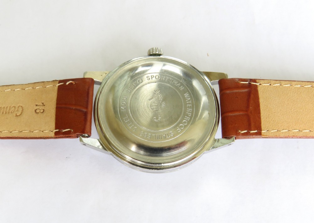A 1960s gents Seiko Sportsman Diashock wristwatch featuring a silver case, champagne dial with baton indices, and a brown leather strap. View IV